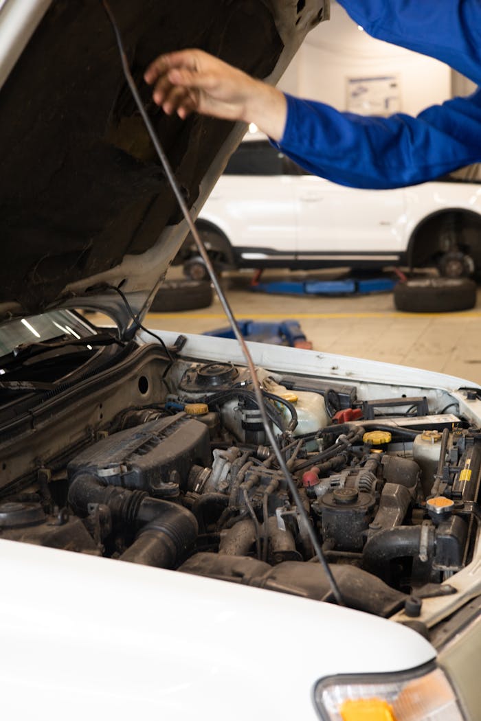 services-02 Close-up of mechanic inspecting car engine under open hood in an auto repair shop.